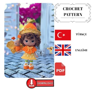 Könnte beinhalten: Eine gehäkelte Puppe in einem orangefarbenen und gelben Outfit, einschließlich Hut, Kleid und Schuhen. Die Puppe hat braune Haare und hält eine kleinere Puppe mit Flügeln. Der Text "CROCHET PATTERN", "ENGLISH", "TÜRKÇE" und "DOWNLOAD" ist enthalten.