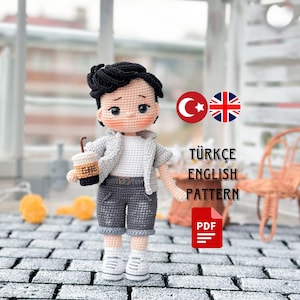 Puede incluir: Patrón de muñeca amigurumi de crochet en turco e inglés. La muñeca sostiene una taza de café y lleva una camisa blanca, pantalones cortos grises y zapatillas blancas. El patrón está disponible para descargar en PDF.