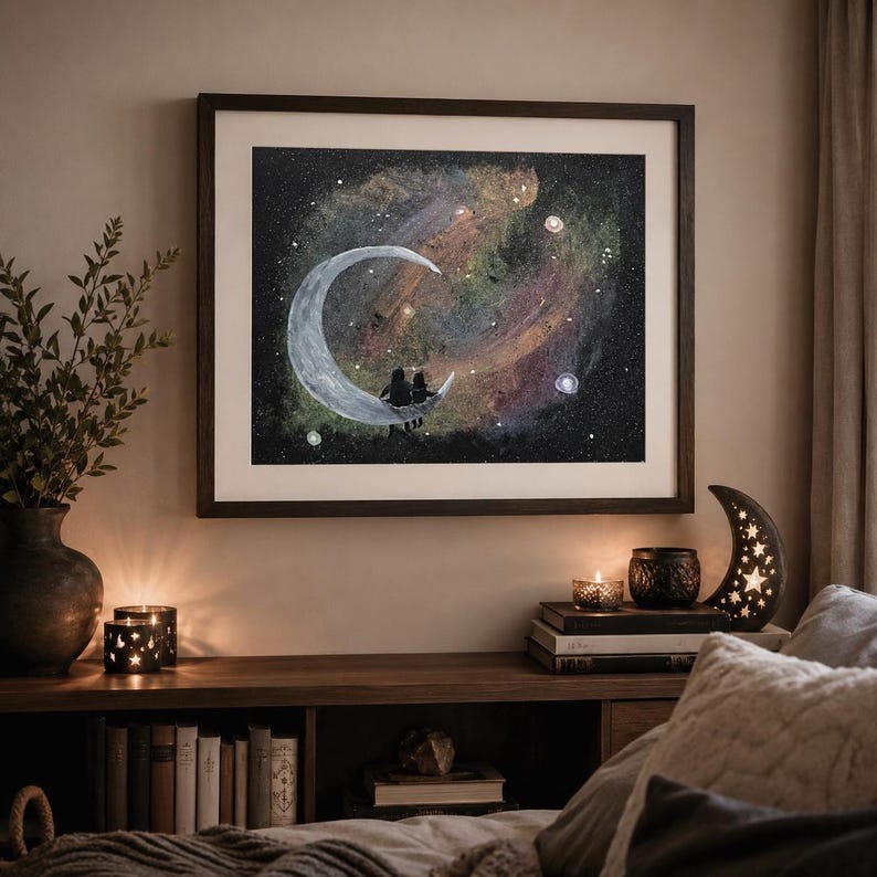 May include: A framed artwork depicts a couple silhouetted on a crescent moon against a colorful galaxy backdrop. The dark wooden frame complements the warm tones of the room, with a decorative moon-shaped lamp and candles adding to the ambiance.