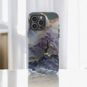 May include: A phone case featuring a serene landscape design. The case showcases a purple tree with a gold-accented mountain range against a marble-like background. The case has a glossy finish and a camera cutout.