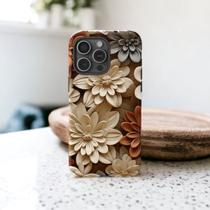 May include: A phone case with a floral design featuring beige and brown 3D flowers. The case has a camera cutout with a black camera lens.