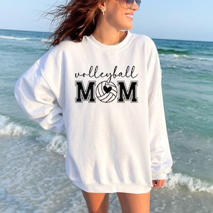 May include: White sweatshirt with black text that reads "volleyball mom" and a black and white volleyball with a heart in the middle.