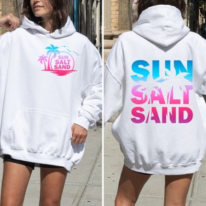 May include: White hoodie with a graphic print of palm trees and the text "SUN SALT SAND" on the front and the same text in a gradient design on the back.