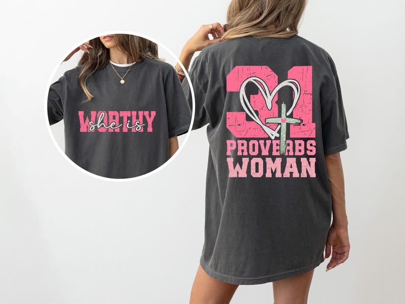 May include: A gray t-shirt with a pink graphic on the back that says "Proverbs 31 Woman" with a heart and cross. The front of the shirt has a pink graphic that says "She is Worthy".