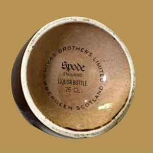 K&ouml;nnte beinhalten: Eine braune Schnapsflasche mit cremefarbenem Rand. Der Boden der Flasche tr&auml;gt den Text "Chivas Brothers Limited" und "Spode England Liquor Bottle 75 CL Aberdeen Scotland" in kreisf&ouml;rmiger Anordnung.