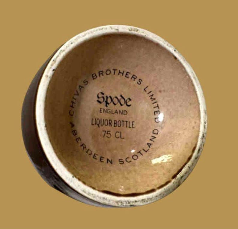 K&ouml;nnte beinhalten: Eine braune Schnapsflasche mit cremefarbenem Rand. Der Boden der Flasche tr&auml;gt den Text "Chivas Brothers Limited" und "Spode England Liquor Bottle 75 CL Aberdeen Scotland" in kreisf&ouml;rmiger Anordnung.