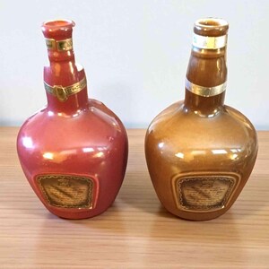K&ouml;nnte beinhalten: Zwei dekorative Keramikflaschen, eine rot-rosa und die andere goldbraun. Beide haben einen abgerundeten Boden, einen schmalen Hals und ein goldenes Band. Jede Flasche hat ein rechteckiges Etikett mit Text.
