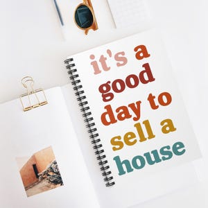 May include: A white spiral notebook with the text "it's a good day to sell a house" in colorful, bold letters. The text is in a rainbow gradient of pink, red, orange, yellow, and blue.