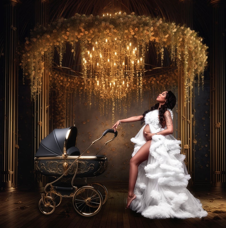 K&ouml;nnte beinhalten: Eine schwangere Person in einem wei&szlig;en, gerafften Kleid steht in einem Raum mit einem goldenen Kronleuchter und Blumendekorationen. Sie schiebt einen schwarzen und goldenen Kinderwagen mit aufwendigen Details.
