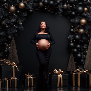 May include: A pregnant woman in a black dress stands in front of a black background with a Christmas tree on either side. The trees are decorated with black and gold ornaments. The woman is holding her belly and looking up.