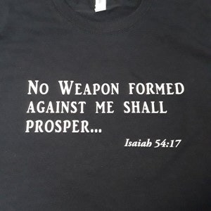 May include: Black t-shirt with white text that reads "No weapon formed against me shall prosper... Isaiah 54:17".
