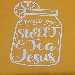 May include: White graphic on a yellow background of a mason jar with a lemon slice on top. The jar says "Raised on Sweet & Tea Jesus".