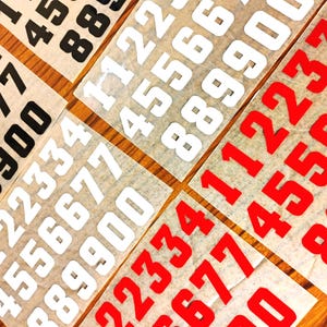 May include: Sheets of white paper with black and red numbers printed on them. The numbers range from 1 to 9.