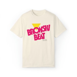 May include: A cream colored t-shirt with a pink and yellow graphic print that says "Bronski Beat London".