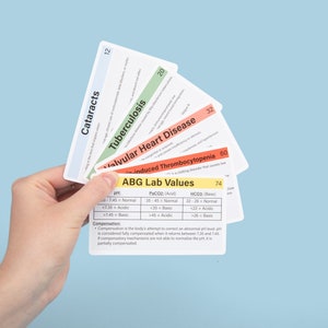 May include: A hand holds a set of flashcards with medical information. The cards display titles like "Cataracts," "Tuberculosis," and "ABG Lab Values." Each card has a different color border and contains text and numerical data. The background is a light blue.