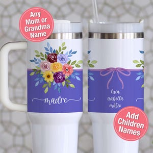 May include: White insulated tumbler with a floral design in purple, yellow, and pink. The tumbler has a handle and a lid with a straw. The word "madre" is written on the tumbler, and the names of children are also displayed.