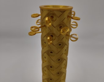 May include: A gold-colored, cylindrical object with a decorative pattern and multiple small, gold-colored keys protruding from the top.