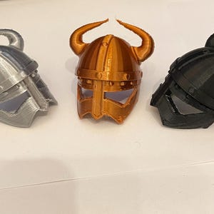 May include: Three miniature Viking helmets, one silver, one copper, and one black.