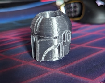 May include: A gray 3D printed figurine of a Mandalorian helmet.
