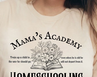 May include: A beige t-shirt with a black graphic design that says "Mama's Academy" with a floral design and an open book with the text "Proverbs 22:6" and the text "Train up a child in the way he should go; even when he is old he will not depart from it." and "HOMESCHOOLING with Grace".