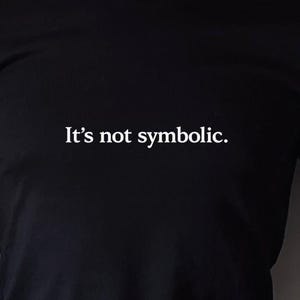 Puede incluir: Una taza de cerámica blanca con un asa negra y el texto "But First, Coffee" en un estilo manuscrito. La taza está sobre una superficie blanca. La taza mide aproximadamente 10 cm de alto.