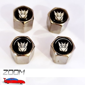 May include: Set of four silver-coloured tyre valve stem caps with a black and white Transformers logo.
