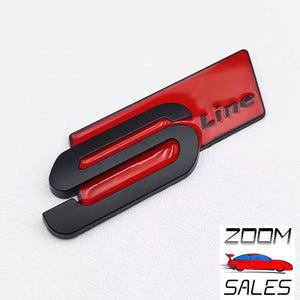 May include: A red and black "S Line" emblem. The emblem features a glossy red background with the word "Line" in white. The "S" is black and has a curved design. Likely a car badge.