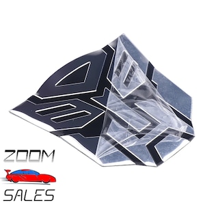 May include: A black and silver metal emblem with a geometric design. The emblem is shaped like a stylised letter 'B' and has a raised, three-dimensional appearance.