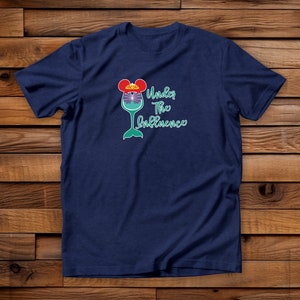 May include: A navy blue t-shirt with a graphic of a wine glass with a mermaid tail and Mickey Mouse ears. The text "Under the Influence" is printed on the shirt.