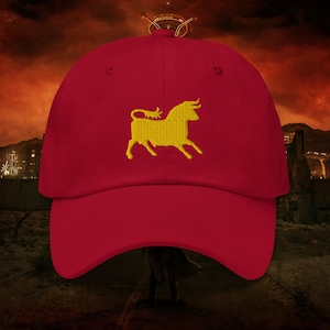 May include: A red baseball cap with a yellow embroidered bull on the front.