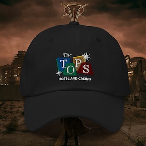 May include: A black baseball cap with an embroidered logo for "The Tops Hotel and Casino". The logo features a colorful block design with the letters "TOPS" and stars.