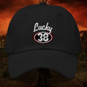 May include: Black baseball cap with an embroidered white logo that says "Lucky 38" in a red oval with a green and white border.
