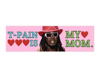 May include: A pink bumper sticker with the text "T-PAIN IS MY MOM" in turquoise and green. The image includes a photo of T-Pain wearing a red hat and sunglasses, with three red hearts.