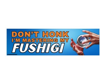 May include: A blue bumper sticker with the text "DON'T HONK I'M MASTERING MY FUSHIGI" in orange and white. The sticker features a graphic of a person's hands holding a reflective sphere with a galaxy design.