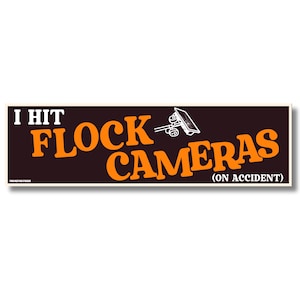 Puede incluir: Una pegatina rectangular para parachoques con fondo marrón oscuro y texto naranja que dice I HIT FLOCK CAMERAS (ON ACCIDENT). Un dibujo lineal blanco de una cámara de vigilancia se encuentra entre las palabras FLOCK y CAMERAS.
