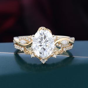 May include: A yellow gold engagement ring set featuring a large oval-cut centre stone surrounded by smaller round and marquise-cut accent stones. The band has a twisted, vine-like design with intricate metalwork and multiple small pavé-set diamonds.