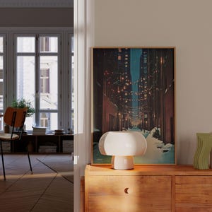 May include: A warm-toned interior scene featuring a wooden dresser with a framed artwork depicting a city street at night. A white mushroom-shaped lamp sits on the dresser, alongside decorative vases. The room has a classic design.