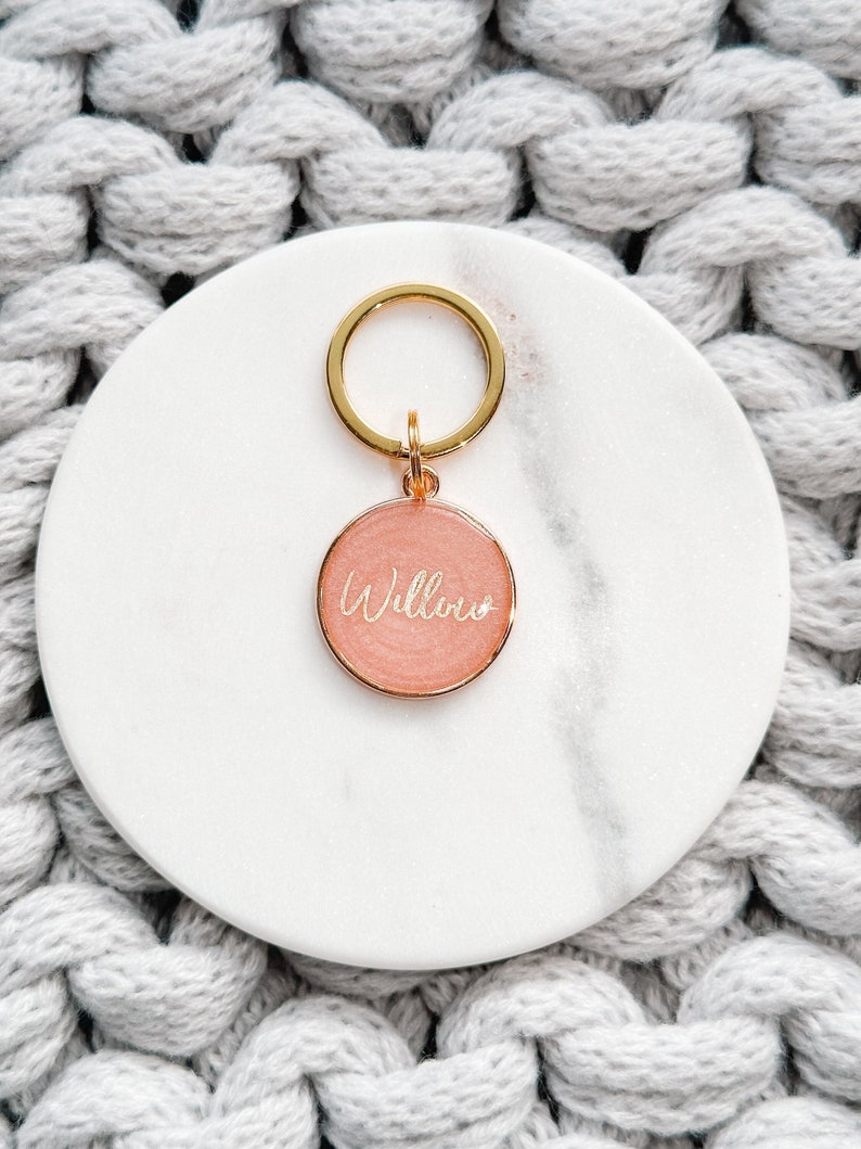 May include: A gold key chain with a pink round tag that says "Willow" in gold lettering.