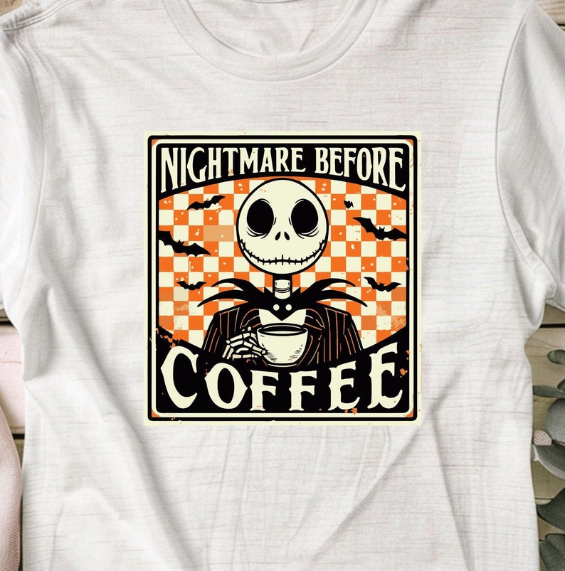 Pode incluir: Uma camiseta branca com um gr&aacute;fico de estilo vintage que apresenta Jack Skellington de "O Estranho Mundo de Jack" segurando uma x&iacute;cara de caf&eacute;. O gr&aacute;fico tem um fundo xadrez com morcegos voando ao redor. O texto diz "Nightmare Before Coffee".