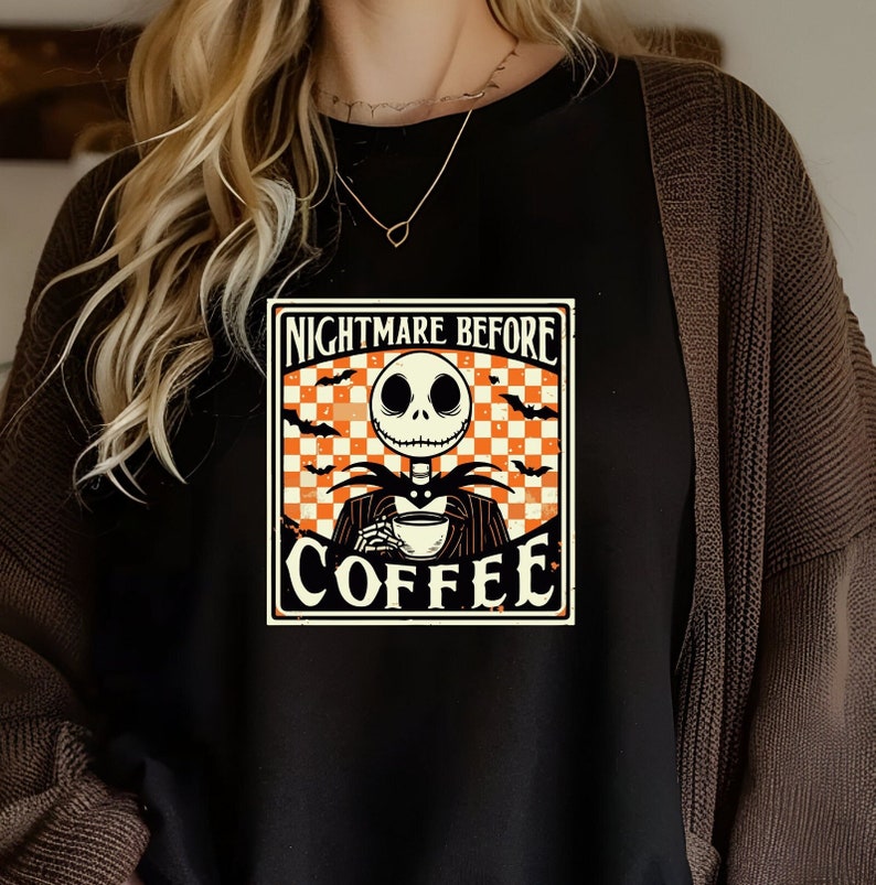 Pode incluir: Camiseta preta com um gr&aacute;fico de estilo vintage de Jack Skellington de O Estranho Mundo de Jack segurando uma x&iacute;cara de caf&eacute;. O gr&aacute;fico diz "Nightmare Before Coffee".