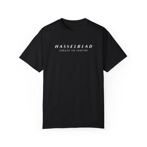 May include: Black t-shirt with white text that reads "HASSELBLAD CREATE TO INSPIRE".