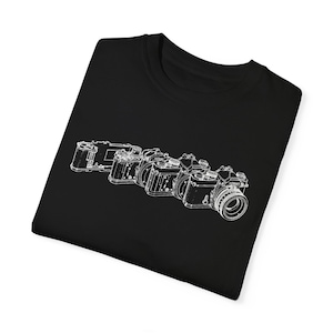 May include: Black t-shirt with a white outline of five different cameras.