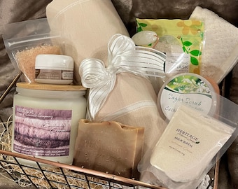 Könnte beinhalten: Ein Spa-Geschenkkorb mit verschiedenen Pflegeprodukten. Enthält eine Kerze, Seife, Badesalz, Zuckerscrub, Milchbad und Körperbutter. Der Korb ist aus Metall und enthält ein beiges Handtuch und ein weißes Band.