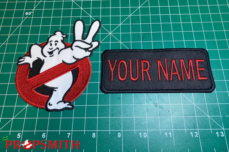 Op de afbeelding: Twee geborduurde patches, een met een witte geest met een rood "geen geest"-symbool en de andere een zwarte patch met de tekst "YOUR NAME" in rood.