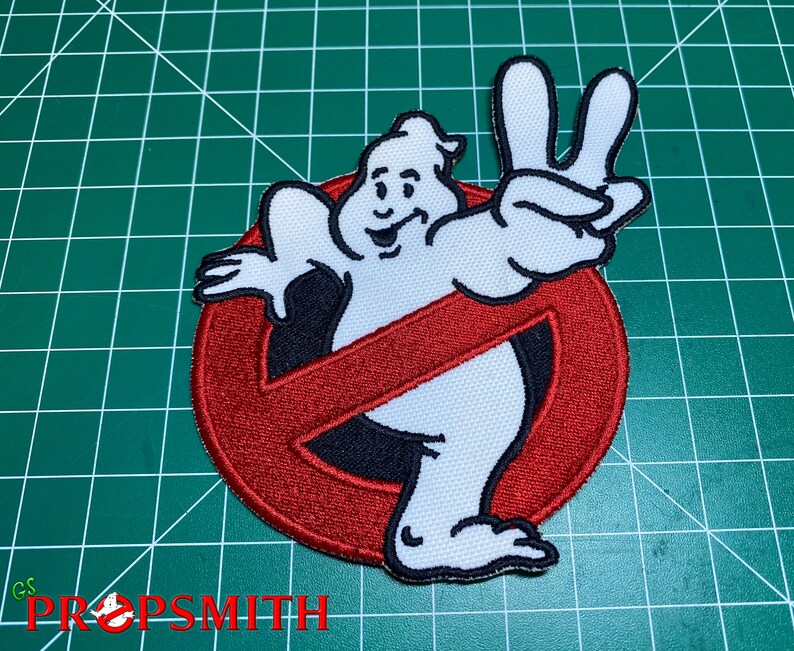 Op de afbeelding: Rode en witte geborduurde patch met het Ghostbusters-logo, een geest met een doorgestreepte cirkel en de geest die een peace-teken maakt.