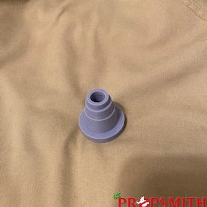 May include: A gray plastic cone-shaped object with a circular base. The object has four layers, each with a slightly smaller diameter than the one below it.