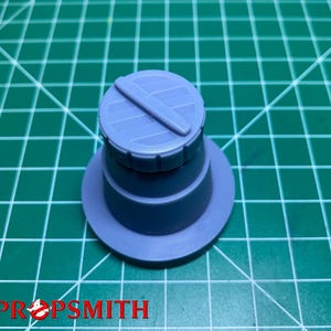 May include: A light blue plastic model of a cylindrical container with a lid. The lid has a grooved design and a small handle.