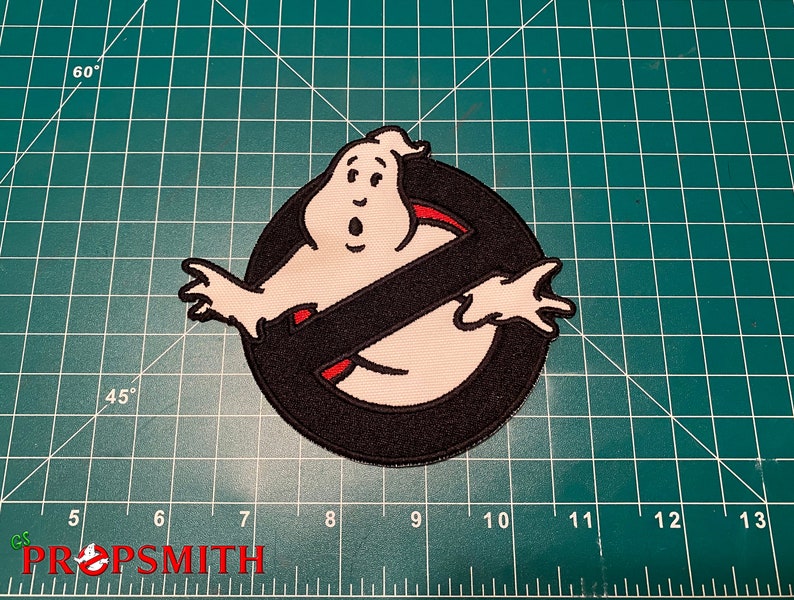 Op de afbeelding: Een geborduurde zwarte en witte patch van het Ghostbusters-logo. Het logo toont een witte geest met een rode omtrek in een zwarte cirkel met een rode schuine streep.