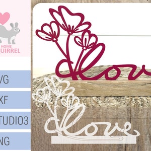 Könnte beinhalten: Ein rotes und weißes Holzschild mit dem Wort "love" in kursivschrift. Das Schild ist mit einem floralen Design verziert.