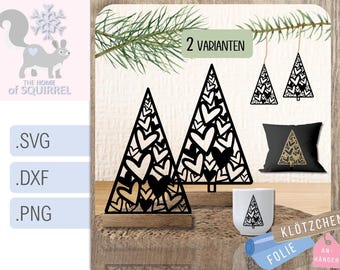 May include: Black laser-cut Christmas tree decorations with heart-shaped cutouts. The image shows two freestanding trees, earrings, a pillow, and a mug, all with the same design. The text "2 VARIANTEN" is visible.